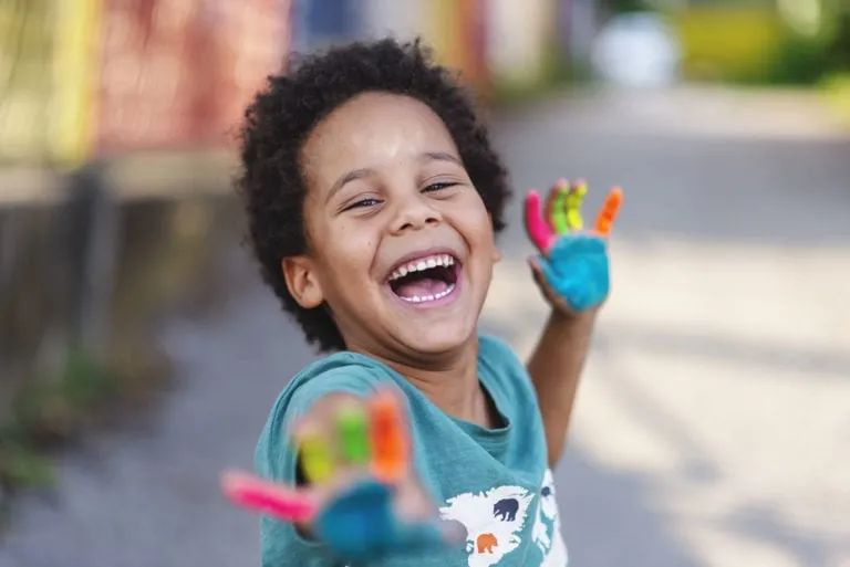 Happy boy with painted hands smiling at Behl Orthodontics