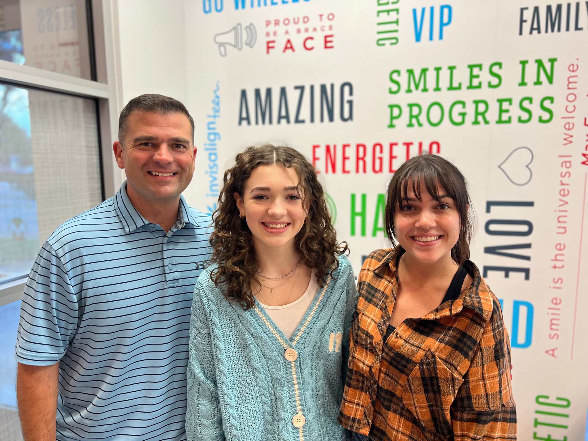 Father and daughters smiling together at Behl Orthodontics