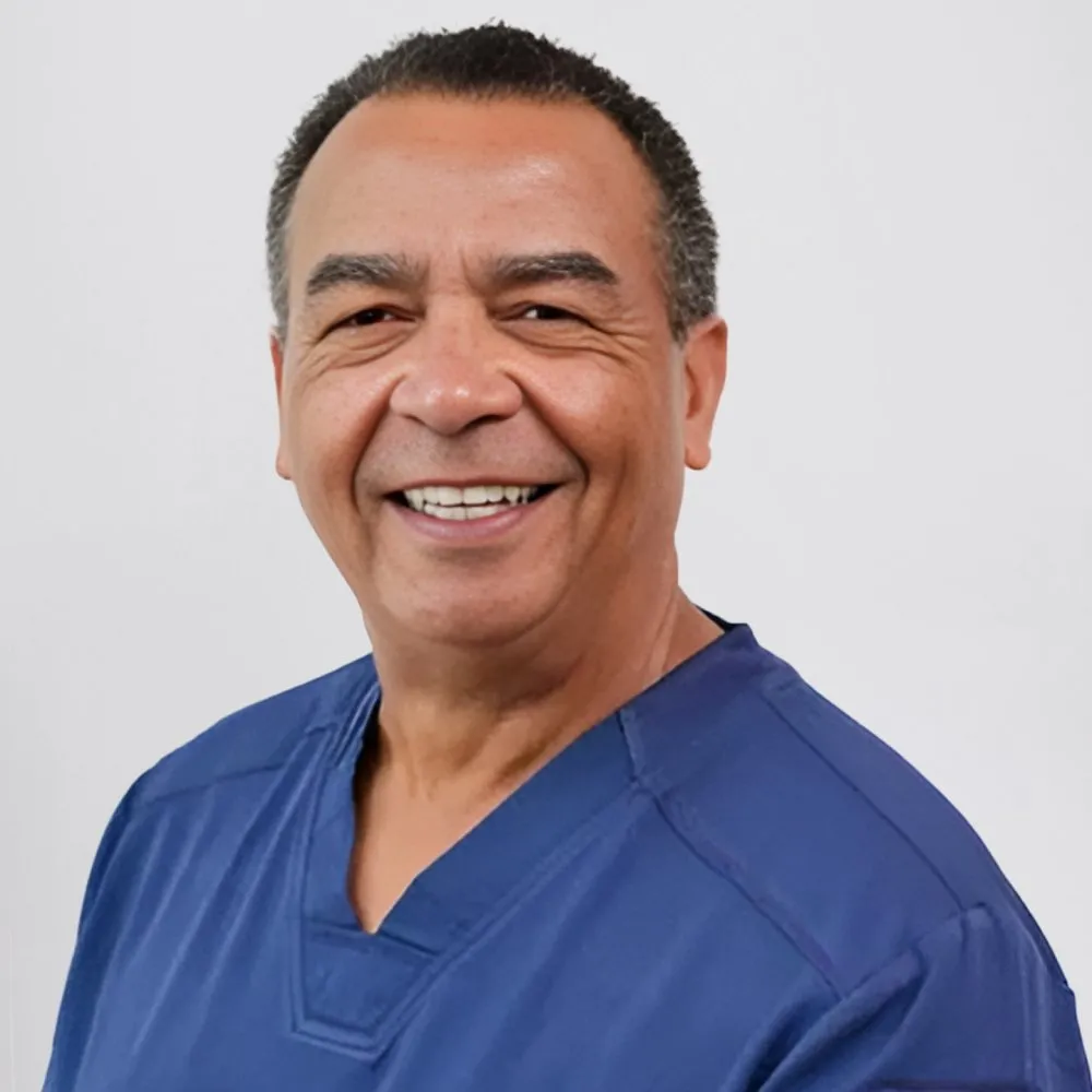 Dr. JB Martin IV smiling in a blue dental scrubs, representing pediatric dentistry expertise at ICON Pediatric Dentistry & Orthodontics.